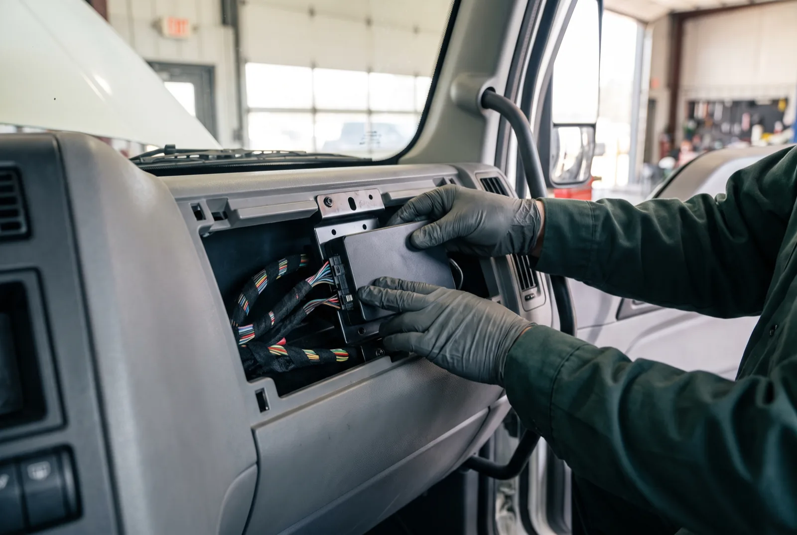 A technician fitting a sealed telematics unit behind a vehicle dashboard